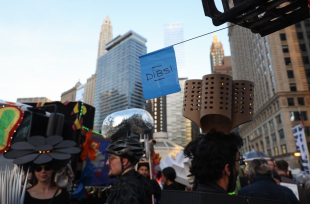 A group of architects wearing headpieces that resemble well-known Chicago buildings and structures mingle before marching in the Arts in the Dark Halloween Parade on Saturday, Oct. 19, 2024. (John J. Kim/Chicago Tribune)