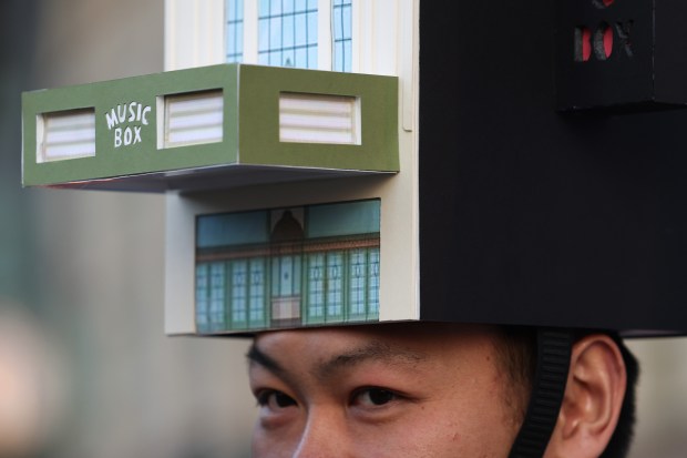 Wei Yu wears a headdress that depicts the Music Box Theatre mingles with fellow architects before marching in the Arts in the Dark Halloween Parade on Oct. 19, 2024. (John J. Kim/Chicago Tribune)