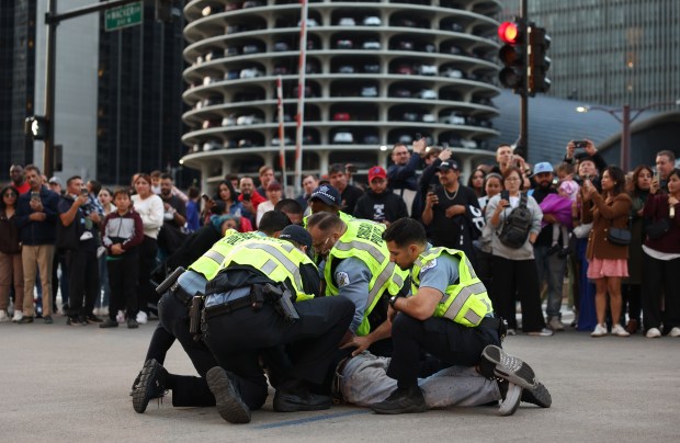 An uncooperative man is detained in front of parade watchers on East Wacker Drive before the Arts in the Dark Halloween Parade. (John J. Kim/Chicago Tribune)