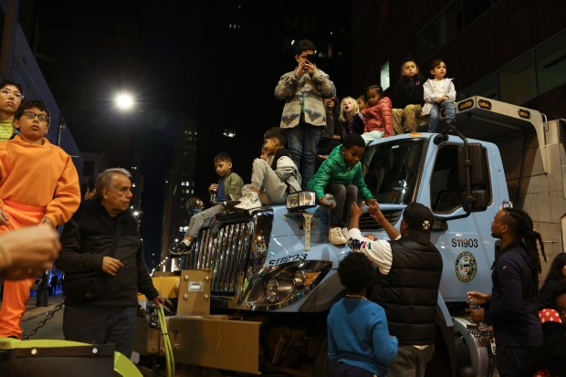 Children get a better view atop a Streets and Sanitation snowplow as they watch the Arts in the Dark Halloween Parade on State Street. (John J. Kim/Chicago Tribune)