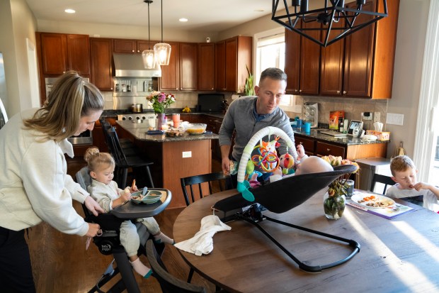 Justin Gwizdala and wife Samantha prepare dinner with their children, Blake, 1, Palmer, 4 months, and James, 3, at their home in Hawthorn Woods on Oct. 15, 2024. The Gwizdala family are currently under contract to sell their Hawthorn Woods home and purchase a new home in Lake Forest. (Ryan Rayburn/for the Chicago Tribune)