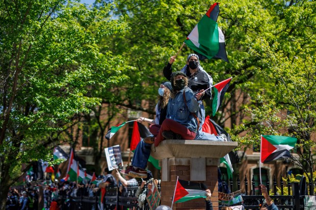 Pro-Palestinian activists stand on a fence with pro-Israel activists stand across the street as members of the Chicago Police department stand between the two groups outside a pro-Palestinian encampment at DePaul University on Sunday, May 5, 2024. (Armando L. Sanchez/Chicago Tribune)