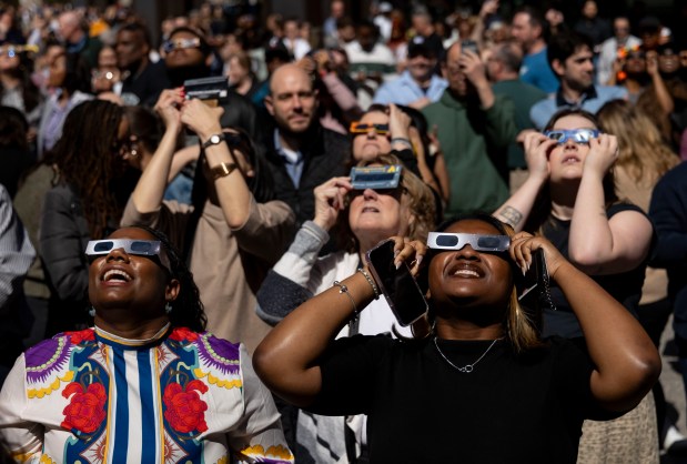 People look up from Daley Plaza to watch the partial solar eclipse over the city on April 8, 2024. (Brian Cassella/Chicago Tribune)