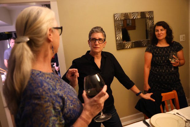 Michal Eskayo, center, relaxes with partner Lynnea Karlic, right, and friend Mary Ramirez, left, as a small group gathers for dinner while celebrating Erev Rosh Hashana on Chicago's Northwest side on Oct. 2, 2024. (Chris Sweda/Chicago Tribune)