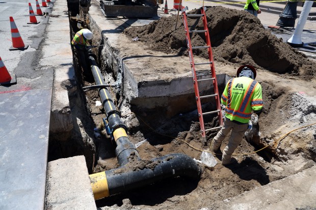 Juan De Luna, left, and Lino Banuelos, from Miller Pipeline, put the finishing touches on a section of a Peoples Gas pipeline replacement project at Wrightwood and Sheffield avenues in Chicago on May 29, 2024. (Terrence Antonio James/Chicago Tribune)