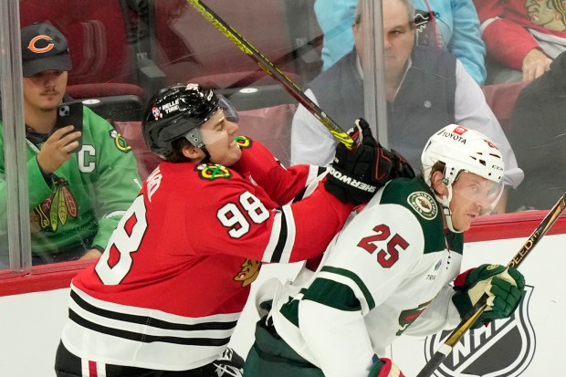 Chicago Blackhawks' Connor Bedard, left, checks Minnesota Wild's Jonas Brodin from behind during the third period of an NHL hockey game Friday, Oct. 4, 2024, in Chicago. (AP Photo/Charles Rex Arbogast)