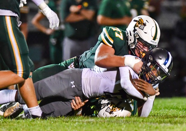 Stefan Popov (77) tackles Oswego East's Jasiah Watson during a nonconference game in Aurora on Friday, Aug. 25, 2023.