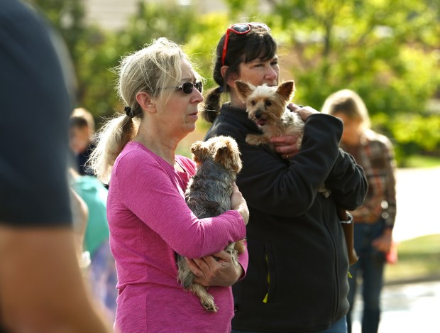 In pink, Marie Maro, a Holy Cross parishioner from Des Plaines and formerly of Norridge and Jody Meyers of Wheeling hold two pups who are sisters, Nikki and Sophie, at the pet blessing at Holy Cross Church in Deerfield on the front lawn of rectory, The House on The Hill on Oct. 5, 2024. (Karie Angell Luc/Lake County News-Sun)