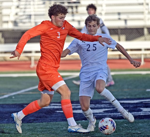 Naperville North's Sam Hess dribbles the ball past Oswego East's Vakaris Majus. Naperville North defeated Oswego East 5-0 in a Class 3A East Aurora Regional championship boys soccer game, Friday, Oct. 25, 2024, in Aurora, Illinois.   (Jon Langham/for the Naperville Sun)