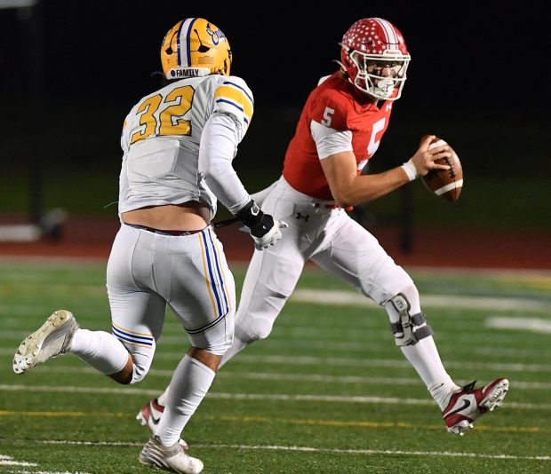 Naperville Central quarterback Sebastian Hayes (5) scrambles away from Sandburg's Evan Benos (32) during a game on Friday, Oct. 18, 2024 in Naperville...(Jon Cunningham/for The Naperville Sun)