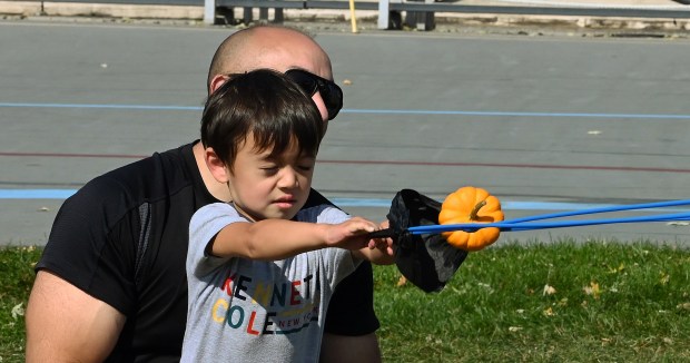 The pumpkin has just been released at the pumpkin chuckin' challenge in the Velodrome. Eyes closed is Joshua Dow, 3, of Skokie who is with his father Jon Dow at Northbrook Autumnfest on Oct. 5, 2024 in Northbrook at Meadowhill Park. (Karie Angell Luc/Pioneer Press)