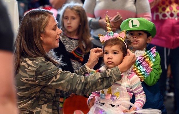 Anna Guerrero of Northbrook adjusts the unicorn headband of Navy, 3. Navy's brother (in green) Aug., 4, is next to Navy. Taken at the Halloween SKELEbration! event in Glenview at the Park Center on Oct. 18, 2024. (Karie Angell Luc/Pioneer Press)