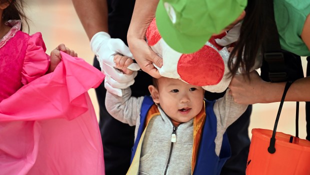 Parent Julie Cimaglio of Glenview puts a Mario franchise hat on tot Dakota, 1, at the Halloween SKELEbration! event in Glenview at the Park Center on Oct. 18, 2024. (Karie Angell Luc/Pioneer Press)