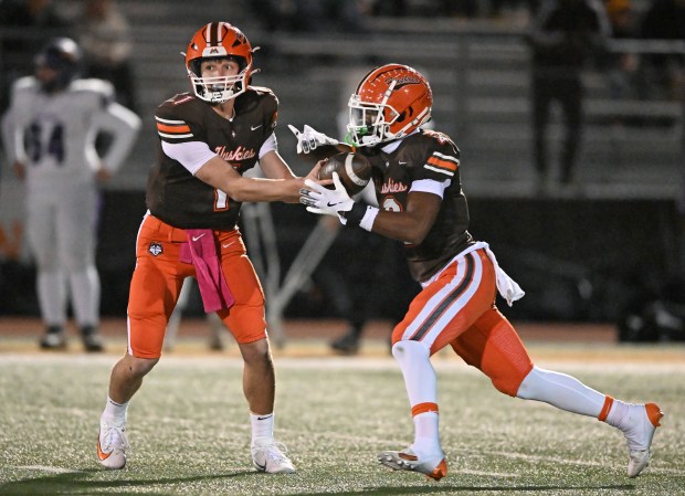 Hersey quarterback, Colton Gumino (1) hands off to Hersey's Brandon Jenkins (2) on a long touchdown run during the 1st quarter of Friday evening's game against Rolling Meadows, Oct. 18, 2024. Hersey won the game, 49-7. (Brian O'Mahoney for the Pioneer Press)