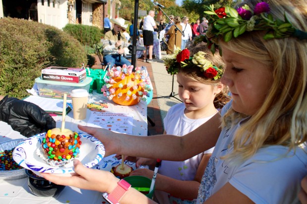 Abby Orr, 7 years old and Annabelle Orr, 8 years old, from Lake Forest participate in caramel apple making and eating during Saturday's Fall Fest.Event activities included fresh produce for sale in the garden market, seasonal and local vendors and artisans selling clothing and culinary treats, live music, games in the paddock, pumpkin painting, caramel apple making, a flower crown craft, farm animal visits and a scavenger hunt, with open doors and outdoor seating available at the new Café at Elawa Farm. (Gina Grillo/ For the Pioneer Press)