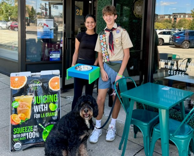 Zac Soles and his dog, Monty, drop off a dog bowl and stand at a downtown La Grange business. Monty inspired Soles' Eagle Scout project because "he gets hot extremely fast,