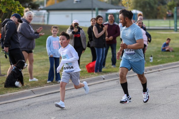 Christopher Solano, 11, and Reynaldo Solano of Niles run in the 11th annual Harvest Hustle 5k in Niles on Saturday, Oct. 12, 2024. The race raises funds for the Niles Family Services Food Pantry. (Troy Stolt / for the Pioneer Press)