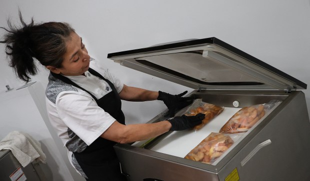 Director of the Faith Farms Fresh Frozen Project, Lucero Martinez seals bags of apples with cinnamon during a demonstration of flash food freezing at the Faith Farms in Gary. Faith Fresh Frozen has started to pack up and flash freeze some of its produce to donate to the Food Bank of NWI as well as other stores on Friday, Oct. 25, 2024. (John Smierciak/for the Post Tribune)