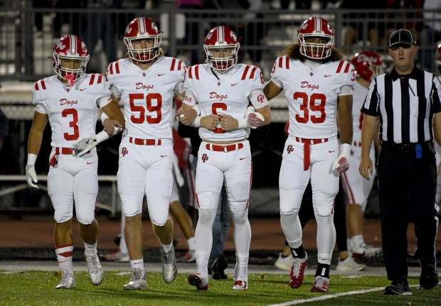 Crown Point quarterback Noah Ehrlich, second from right, leads teammates Larry Ellison, Josh Miller and Trevor Gibbs to the coin flip prior to the Bulldogs' game against the Vikings in Valparaiso, Indiana Friday Sept. 27, 2024. Crown Point went on to win 41-7. (Andy Lavalley for the Post-Tribune)