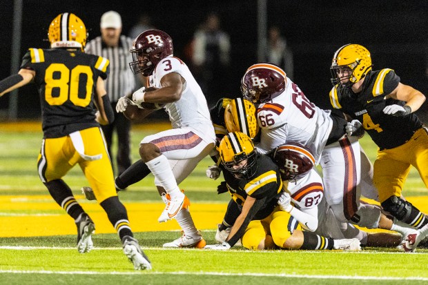 Brother Rice's Tyler Lofton (3) gets past a pair of St. Laurence defenders with a little help from his offensive line during a CCL/ESCC crossover game in Burbank on Friday, Oct. 18, 2024. (Vincent D. Johnson / for the Daily Southtown)