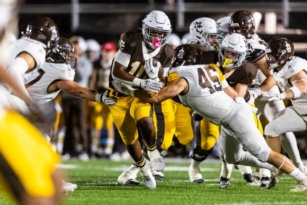 Mount Carmel's Danyil Taylor (10) breaks through the line as Joliet Catholic's Nick Bueno (45) tries to tackle him during a CCL/ESCC crossover game in Chicago on Friday, Oct. 11, 2024. (Vincent D. Johnson / for the Daily Southtown)