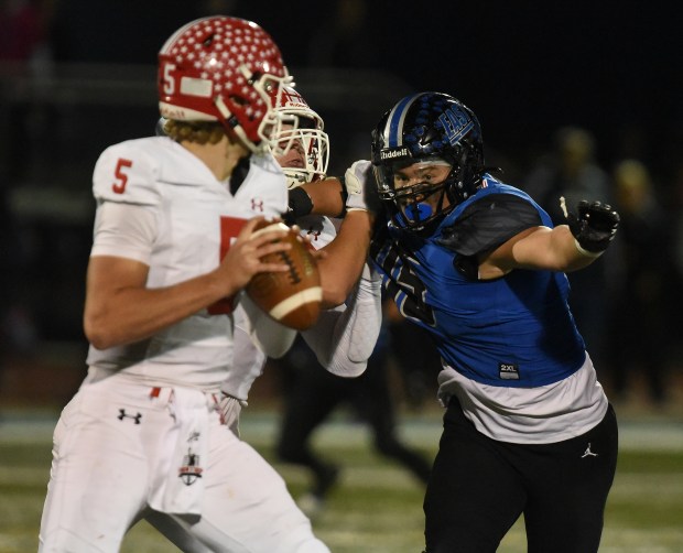 Naperville Central's Sebastian Hayes (5) stands in the pocket as Lincoln-Way East's Michael Jemilo (95) puts pressure on him during a Southwest Valley Conference game Friday, Oct. 25, 2024 in Frankfort, IL. (Steve Johnston/for the Daily Southtown)