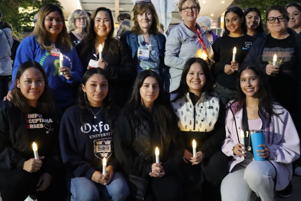 St. Xavier nursing students pose with associate professors Mary Murphy Smith and Jean Kirk before a candlelight vigil Oct. 10, 2024 to bring awareness to domestic violence. (Susan DeGrane/for the Daily Southtown)