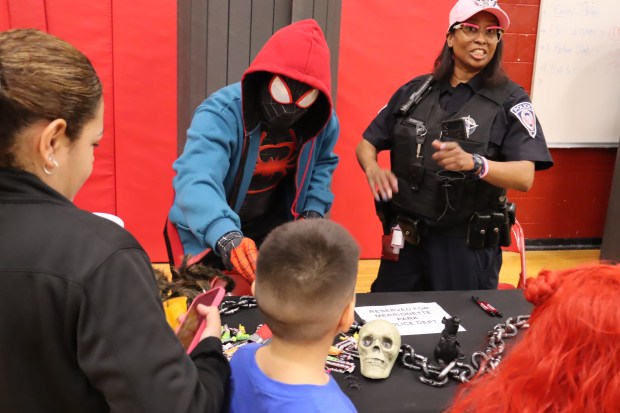 Merrionette Park police Officers Davon Sangster, dressed as Spider-Man, and Rhea Robinson pass out treats to children Tuesday at the Eisenhower Spooktacular in Blue Island. (Susan DeGrane/Daily Southtown)