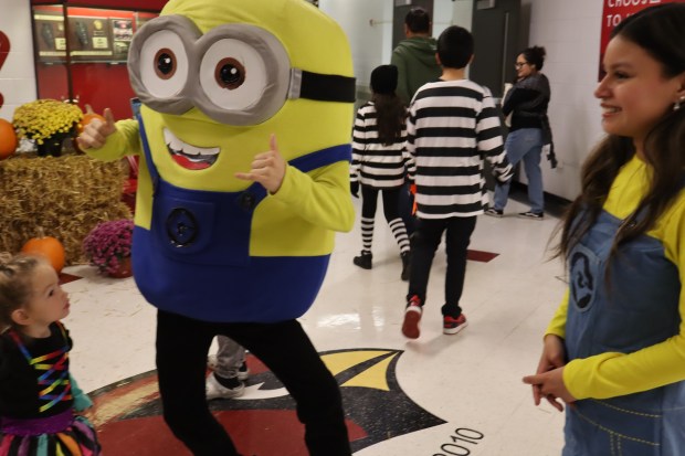 Dressed as Bob the Minion, Nicholas Navarrete, a senior at Eisenhower High School in Blue Island, engages with a trick-or-treater Tuesday at the school's annual Spooktacular, as Itzel Trinidad, a junior, helps out. (Susan DeGrane/Daily Southtown)