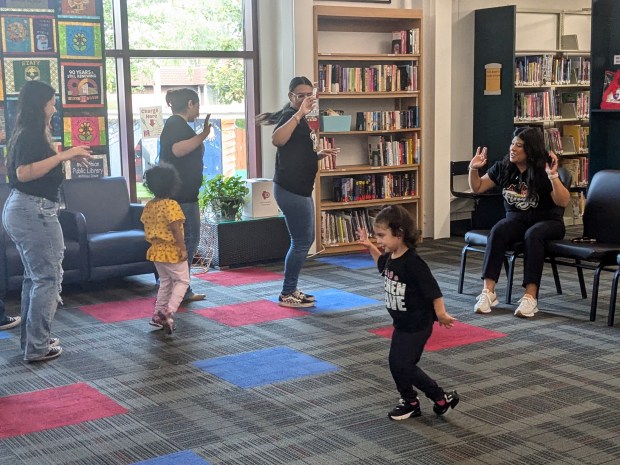 Mayra Martinez, who sponsors the Fuego Dance Group at Bremen High School, shows students and children some of the Latin dance moves before their performance Oct. 12, 2024, at the Midlothian Public Library. (Janice Neumann/for the Daily Southtown)