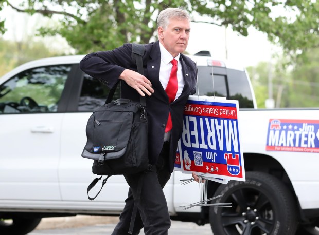 James Marter carries campaign lawn signs before an event at a banquet hall, May 17, 2022, in Glen Ellyn. (John J. Kim/Chicago Tribune)