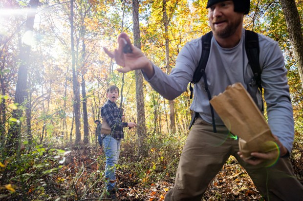 John Willis, 12, left, looks in awe at a blewit mushroom that Gino Albert found with the Illinois Mycological Association at the St. Mihiel Woods-East nature preserve in Tinley Park on Oct. 26, 2024. (Tess Crowley/Chicago Tribune)