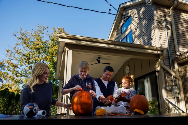 From left, Kelly Stempel, her daughter, Elin, 11, husband, Adam, and daughter Leighton, 9, carve pumpkins in their backyard on Oct. 27, 2024, in Villa Park. (Armando L. Sanchez/Chicago Tribune)