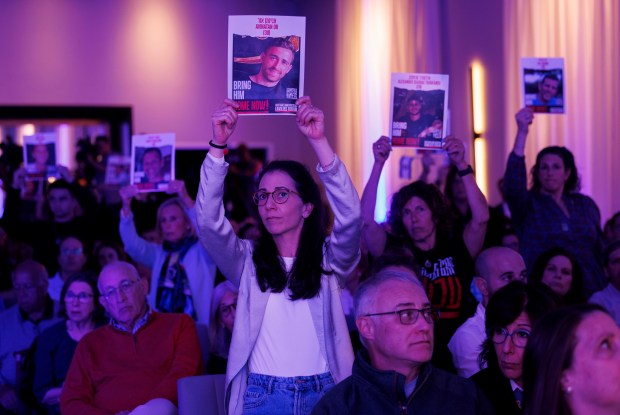 Attendees hold photos of people taken hostage during the Oct. 7, 2023 Tribe of Nova music festival attack by Hamas during a memorial Monday night hosted by the Jewish United Fund in Skokie. (Armando L. Sanchez/Chicago Tribune)