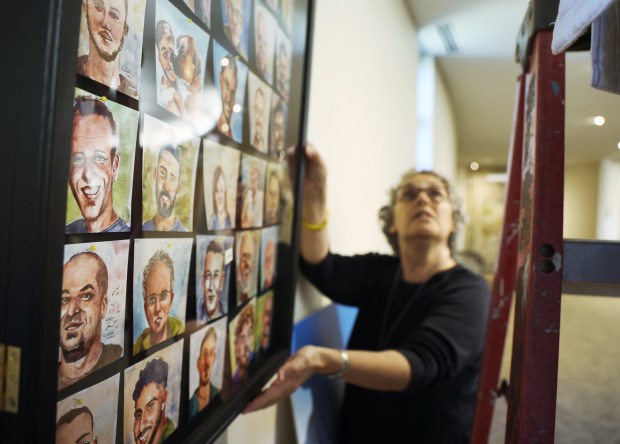 Marcie Eskin hangs art work of Israeli hostages on a wall at North Suburban Synagogue Beth El on Sept. 30, 2024, in Highland Park. (Stacey Wescott/Chicago Tribune)