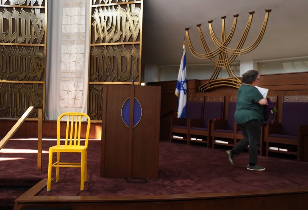 Hazzan Jenna Greenberg passes by an empty chair at North Suburban Synagogue Beth El on Sept. 30, 2024, in Highland Park. The empty yellow chair is kept on the Bimah as a reminder of the hostages taken by Hamas on Oct. 7th. (Stacey Wescott/Chicago Tribune)