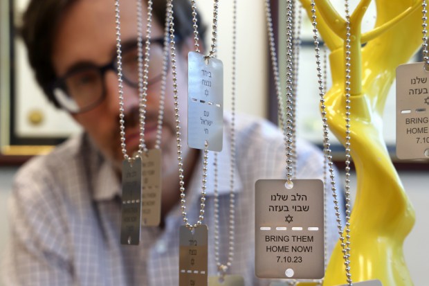 Rabbi Alex Freedman poses behind dog tag necklaces inscribed with the message BRING THEM HOME NOW in English and Hebrew at North Suburban Synagogue Beth El on Sept. 30, 2024, in Highland Park. (Stacey Wescott/Chicago Tribune)