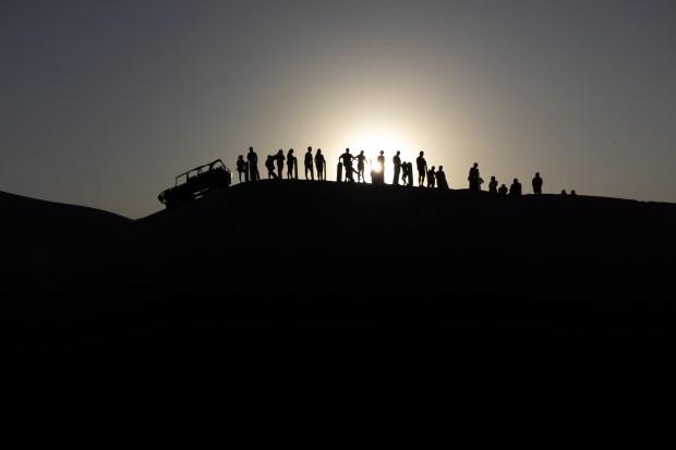 People watch a sunset from atop one of the sand dunes in Huacachina, near Ica, Peru, Aug. 23, 2024. (Angela Ponce/The New York Times)