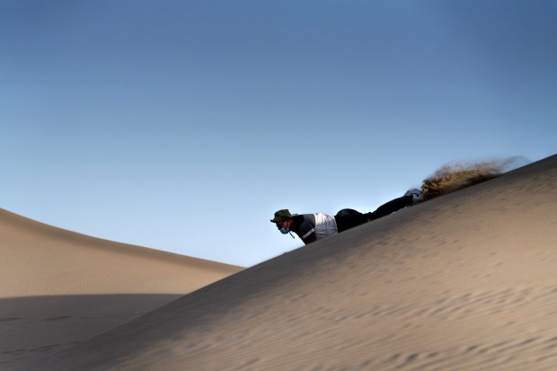 A tourist tries sand boarding down a sand dune in Huacachina, near Ica, Peru, Aug. 24, 2024. (Angela Ponce/The New York Times)