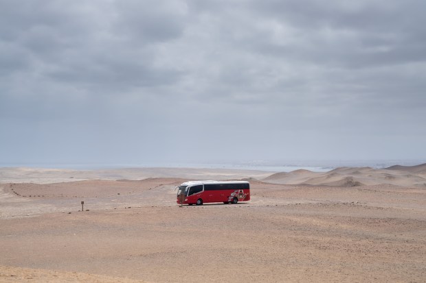 A Peru Hop bus travels through the desert of the Paracas National Reserve, a protected area near Ica, Peru, Aug. 23, 2024. The roughly decade-old Peru Hop service lets travelers choose a bus route and then decide how much time they want to spend at each stop along the way. (Angela Ponce/The New York Times)