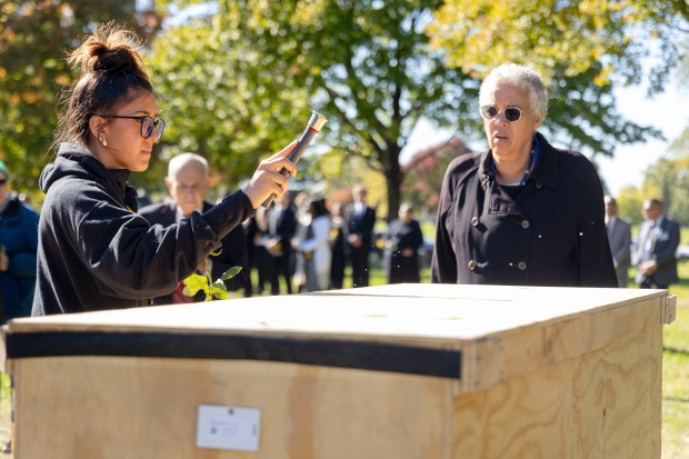 Faith Arenibar of St. Laurence High School sprinkles holy water alongside Cook County Board President Toni Preckwinkle on Oct. 16, 2024, at Mt. Olivet Cemetery. (Brian Cassella/Chicago Tribune)