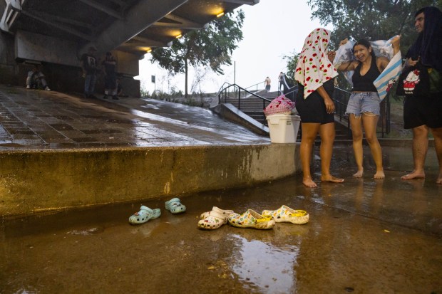 People take cover under the Ohio Street underpass while a storm rolls in after a day of the heat index at triple digits on Aug. 27, 2024. (Tess Crowley/Chicago Tribune)