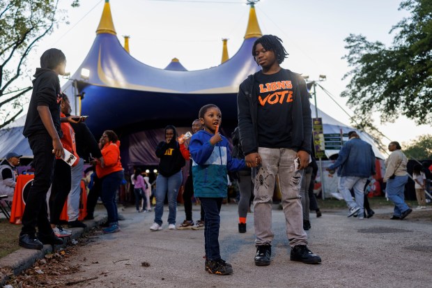 Zyaire Campbell, 16, with help from five year-old Kaliq Richardson-Williams, waits to talk with attendees about registering to vote outside the UniverSoul Circus in Washington Park on Oct. 2, 2024, in Chicago. (Armando L. Sanchez/Chicago Tribune)