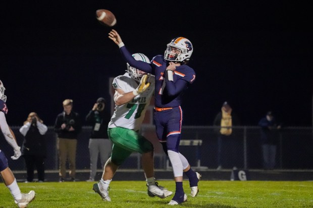 Oswego's Brett Connolly (7) throws a pass while being pressured by York's Joe Reiff (78) during a 8A second-round football playoff game at Oswego High School on Friday, Nov 8, 2024. (Sean King / for The Beacon-News)