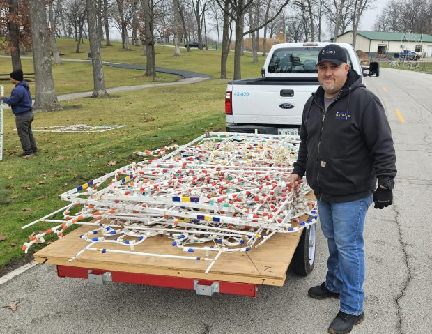 Juan Leon stands near pieces of a display to be set up at Phillips Park on Monday for the 18th annual Festival of Lights, which begins Friday. Leon was overseeing a crew putting up the installation. (David Sharos / For The Beacon-News)