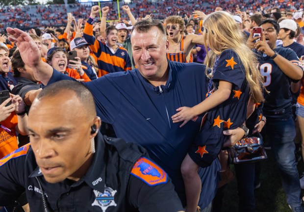 Illinois coach Bret Bielema walks off the field with his daughter after a win over Michigan at Memorial Stadium on Oct. 19, 2024, in Champaign. (Michael Hickey/Getty Images)