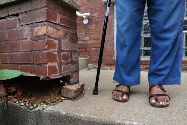 Claire Addams-Hoffman stands beside cracked and crumbling bricks outside her residence at the Chatham Park Village Cooperative in Chicago on Thursday, Aug. 17, 2023. (Chris Sweda/Chicago Tribune)