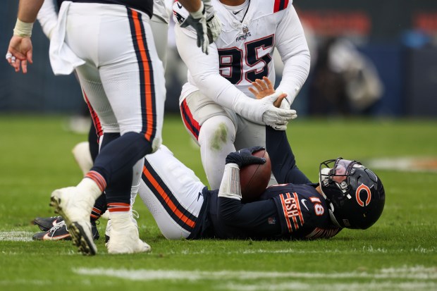 New England Patriots defensive tackle Daniel Ekuale (95) helps Chicago Bears quarterback Caleb Williams (18) up after sacking him during the fourth quarter at Soldier Field on Nov. 10, 2024. (Eileen T. Meslar/Chicago Tribune)