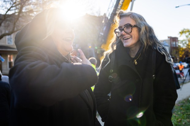 Current resident Sarah Holden, right, talks to neighbor Nilda Garcia before workers cut down Chicago's 2024 Christmas tree, a 53-foot Colorado blue spruce in Logan Square neighborhood on Nov. 1, 2024. (Tess Crowley/Chicago Tribune)