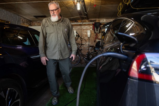 Tony Adams, 62, checks on his new Tesla as it charges in his garage in the McKinley Park neighborhood of Chicago on Oct. 25, 2024. (Tess Crowley/Chicago Tribune)